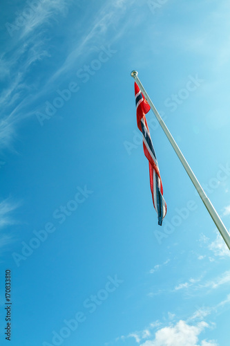 The National flag of Norway blowing in the wind in front of a clear blue sky