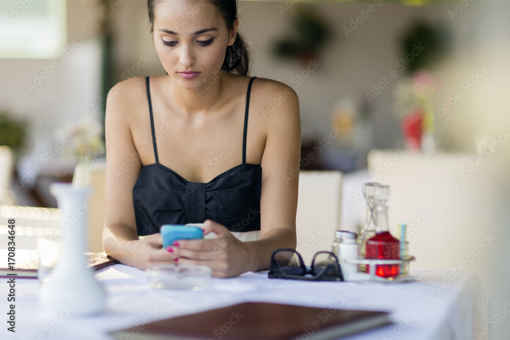 Beautiful woman using phone while waiting for meal in restaurant Beautiful woman using phone while waiting for meal in restaurant