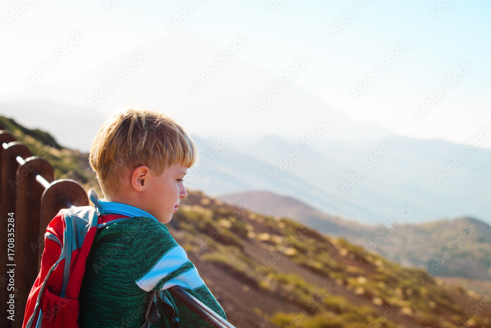 little boy hiking looking at view in mountains