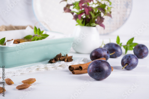 Group of fresh purple  plums on a white kitchen table ready for cooking