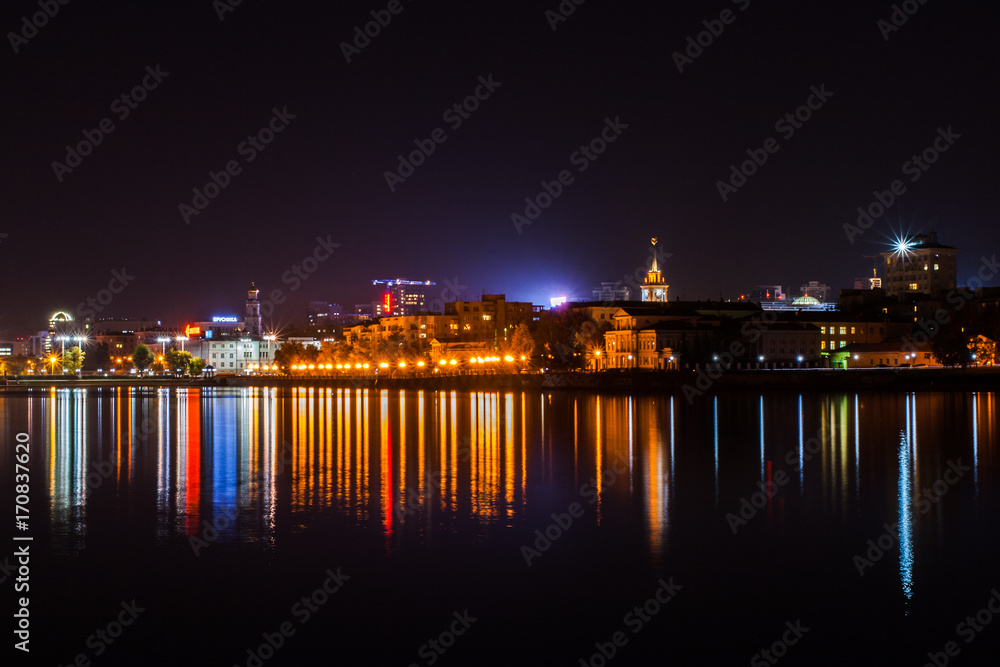 Yekaterinburg, Russia - September,26,2016: Evening city lights and their reflection in water of pond.