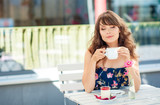 Beautiful young woman sits in a cafe. A girl drinks coffee and eats dessert. A young woman is walking around the city.