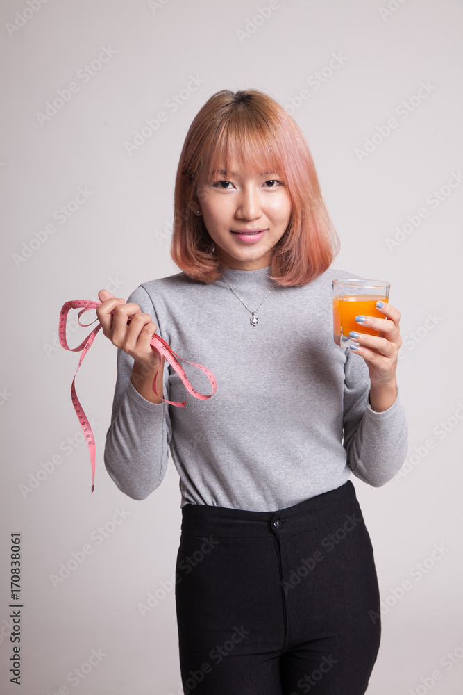 Asian woman drink orange juice hold measuring tape. Asian woman drink orange juice hold measuring tape.