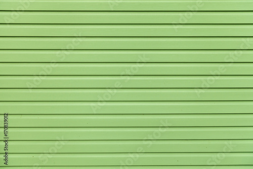 Green vinyl wooden siding panel background with imitation wood texture.