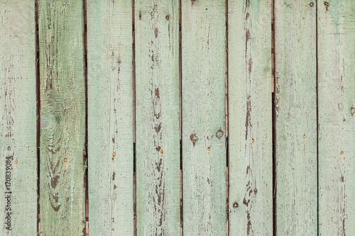 Old rural fence. Shabby Wood Background with old light green paint. Close up