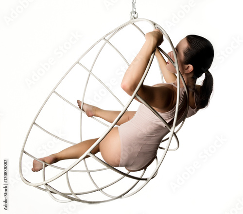 sexy woman in a beige swimsuit on a metal cage on a white background