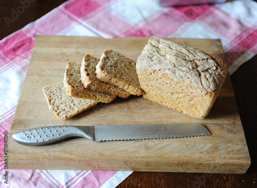 Fresh bread on a rye ferment without yeast cut on a wooden cutting board on a checkered tablecloth