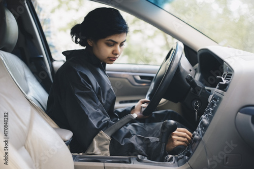 Female mechanic adjusting knob on dashboard in car