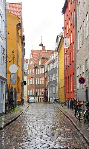 Colorful street  red  blue and yellow houses and bikes with basket in old town  rainy day  Copenhagen  Denmark