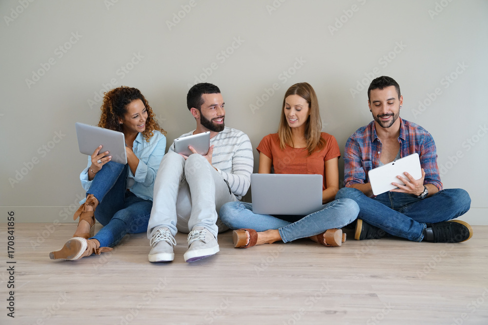 Group of friends using laptop and tablet, sitted on floor