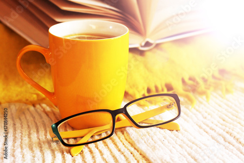 Yellow mug of tea, book and glasses, autumn mood
