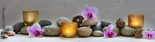 Photo concept of wellbeing with pebbles, orchids and candles, panoramic