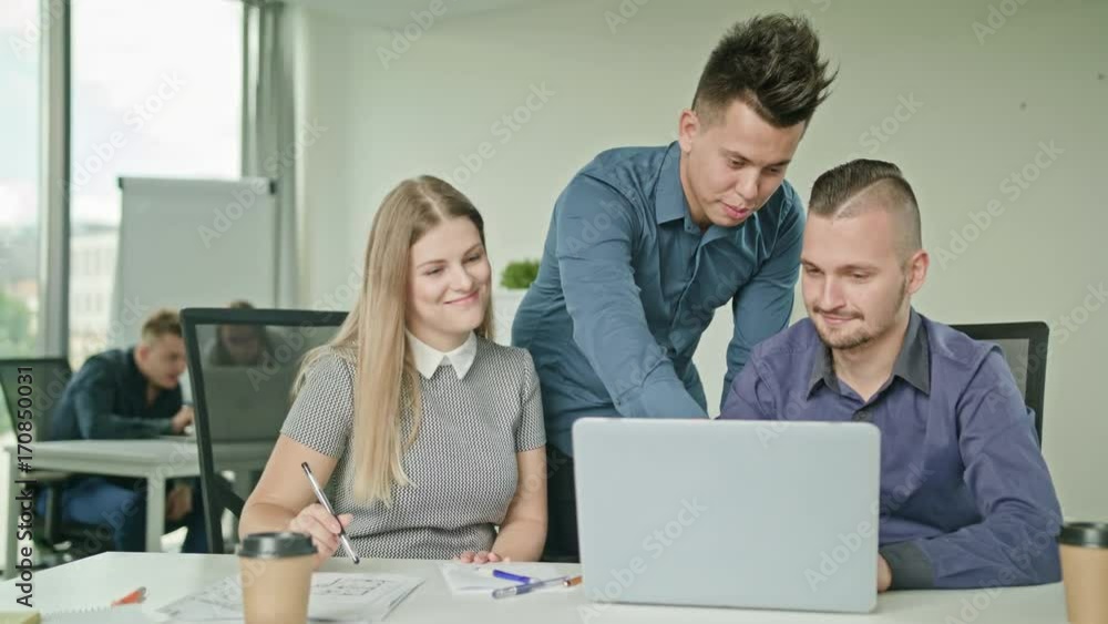 Creative business team meeting in modern start up office male team leader pointing at screen discussing diverse people group teamwork using laptop display Creative business team meeting in modern start up office male team leader pointing at screen discussing diverse people group teamwork using laptop display