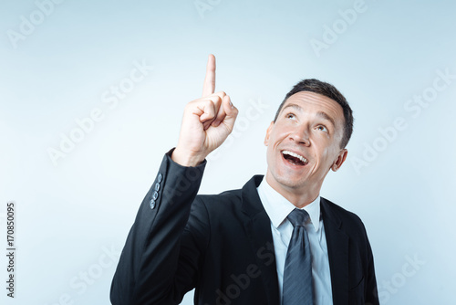 Cheerful positive man pointing up with his finger