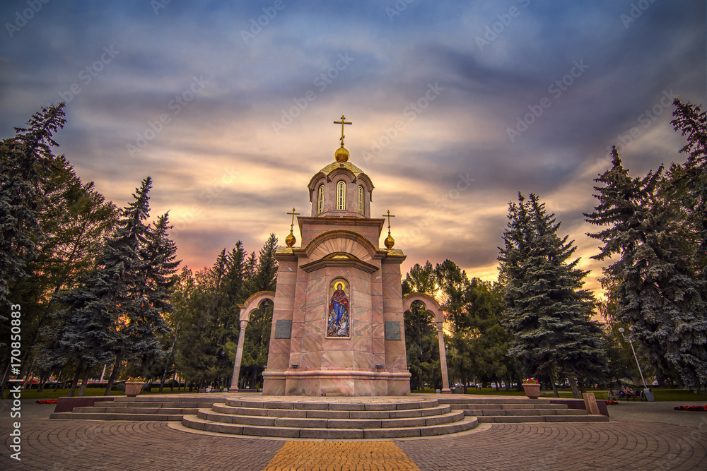 Sunset view of small Chapel surrounded by trees with colorful sky in Kemerovo downtown Siberia? Russia