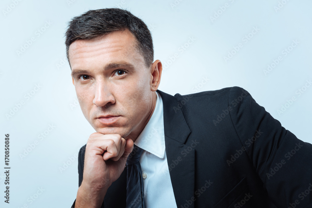Pleasant pensive man resting his chin on the hand Pleasant pensive man resting his chin on the hand