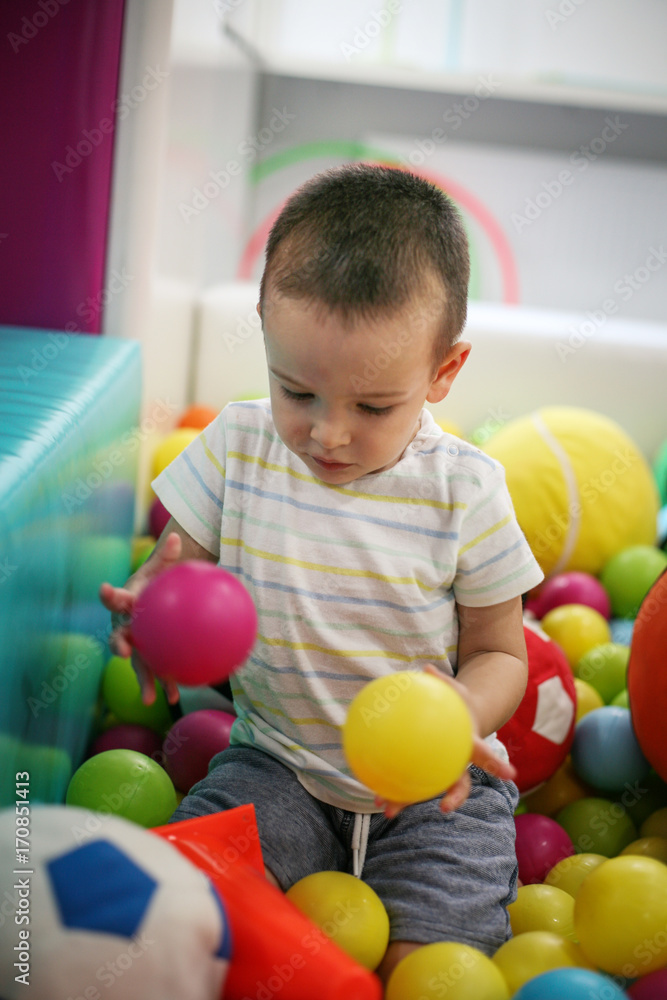 Fototapeta premium Little boy in playground. Caucasian little boy playing with colored ball.