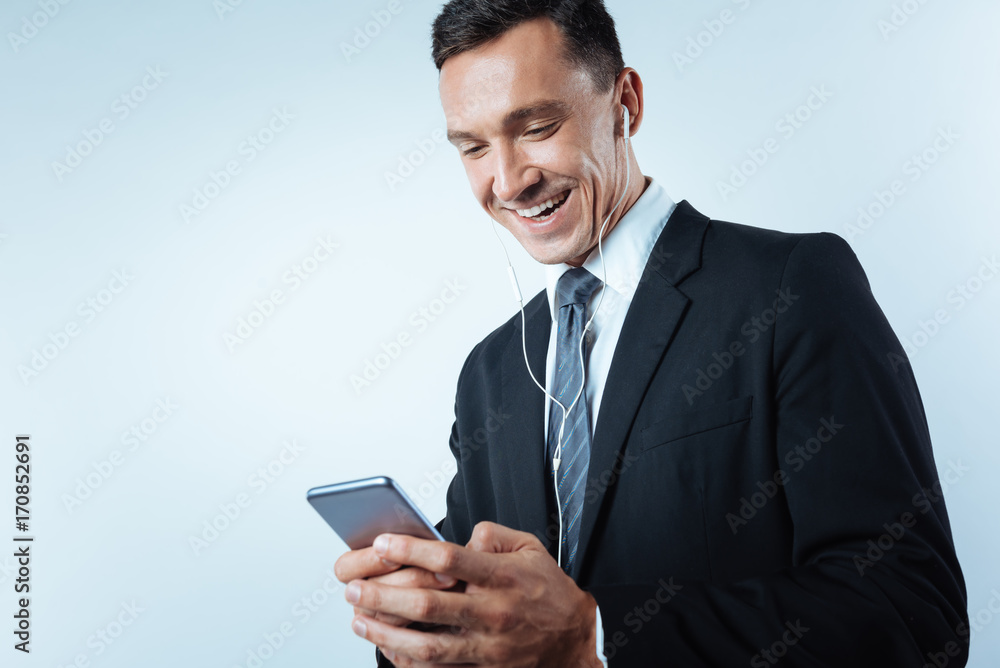 Cheerful joyful man using his smartphone Cheerful joyful man using his smartphone