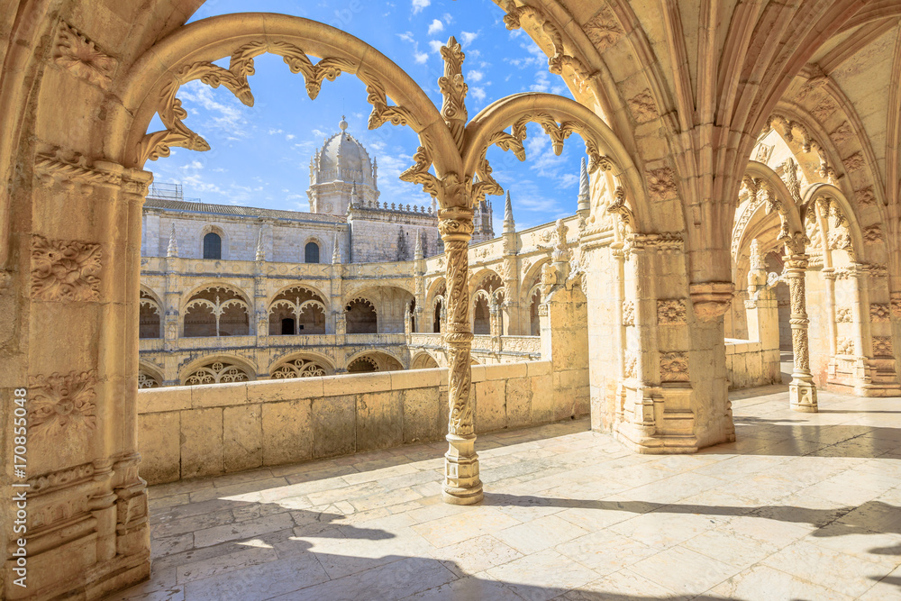 Beautiful reticulated vaulting on courtyard or cloisters of Hieronymites Monastery, Mosteiro dos Jeronimos, famous Lisbon landmark in Belem district and Unesco Heritage. Church dome on background.