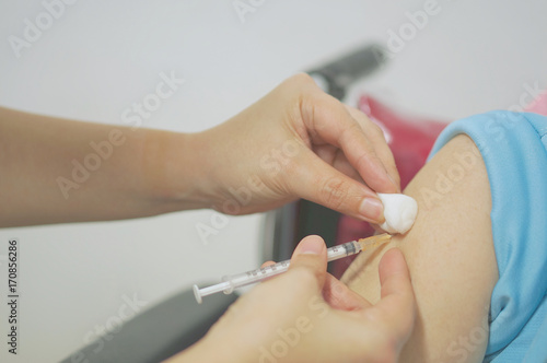 Nurse holding hypodermic syringe and cotton ball has injected vaccine