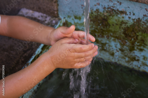 kid washing hand in public water fountain