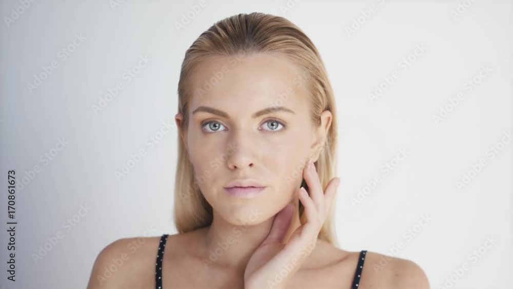 Portrait of happy smiling beautiful young woman touching skin or applying cream, after shower with towel on head Portrait of happy smiling beautiful young woman touching skin or applying cream, after shower with towel on head