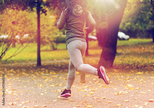 close up of young woman running in autumn park