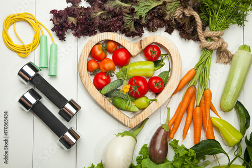 Sports and diet. Fresh vegetables, tomatoes, lettuce and carrot salad on a white wooden background