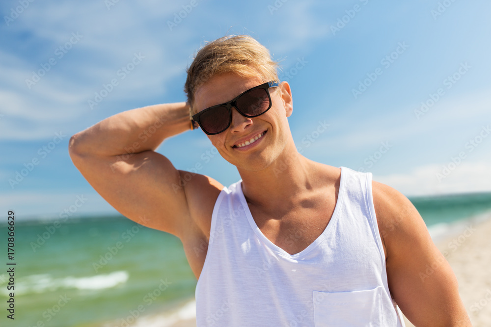 smiling young man in sunglasses on summer beach smiling young man in sunglasses on summer beach