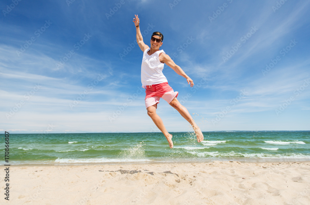 smiling young man jumping on summer beach smiling young man jumping on summer beach