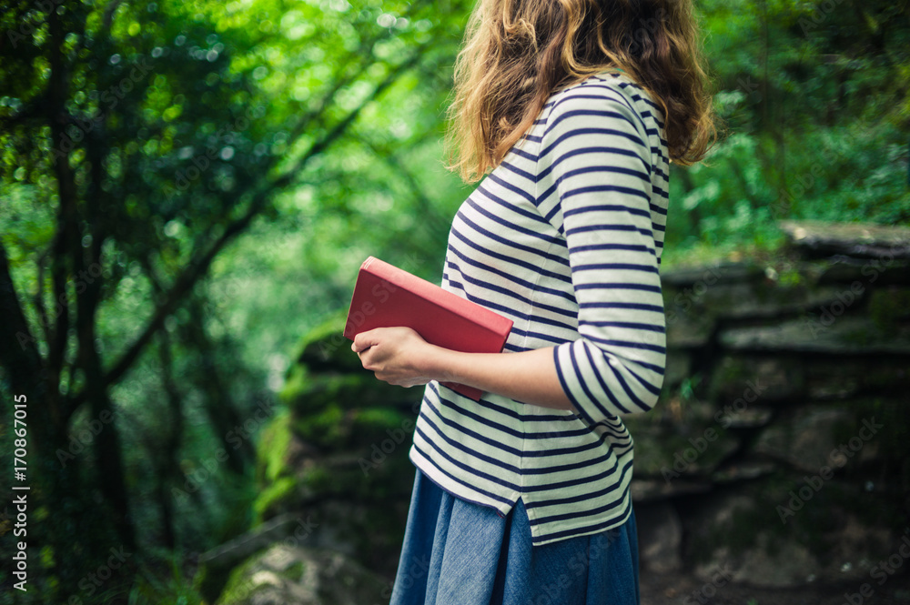 Woman with book standing in the forest