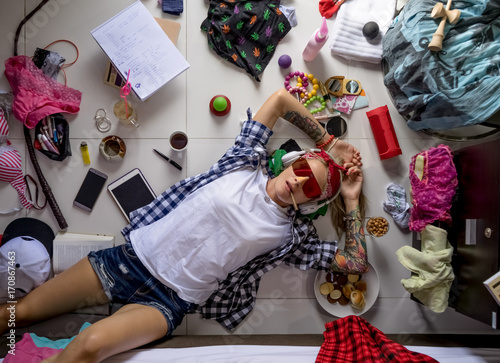 Student girl in a plaid shirt listening to music and thinking about the upcoming study at the University, lying on the floor. The mess in the ladies ' room, the image of the modern girl student. photo