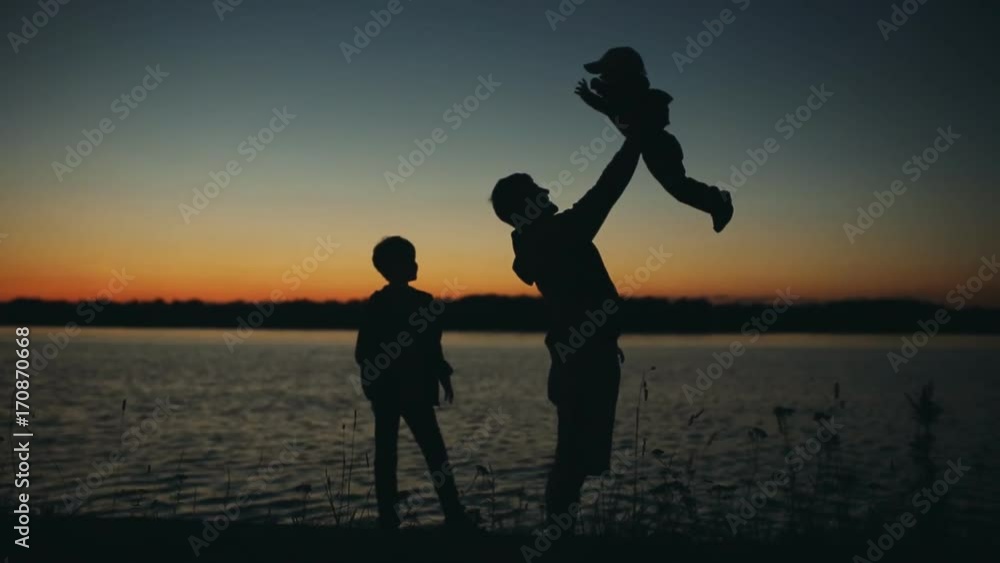 Father and son playing in the park at sunset silhouette of a happy family Father and son playing in the park at sunset silhouette of a happy family