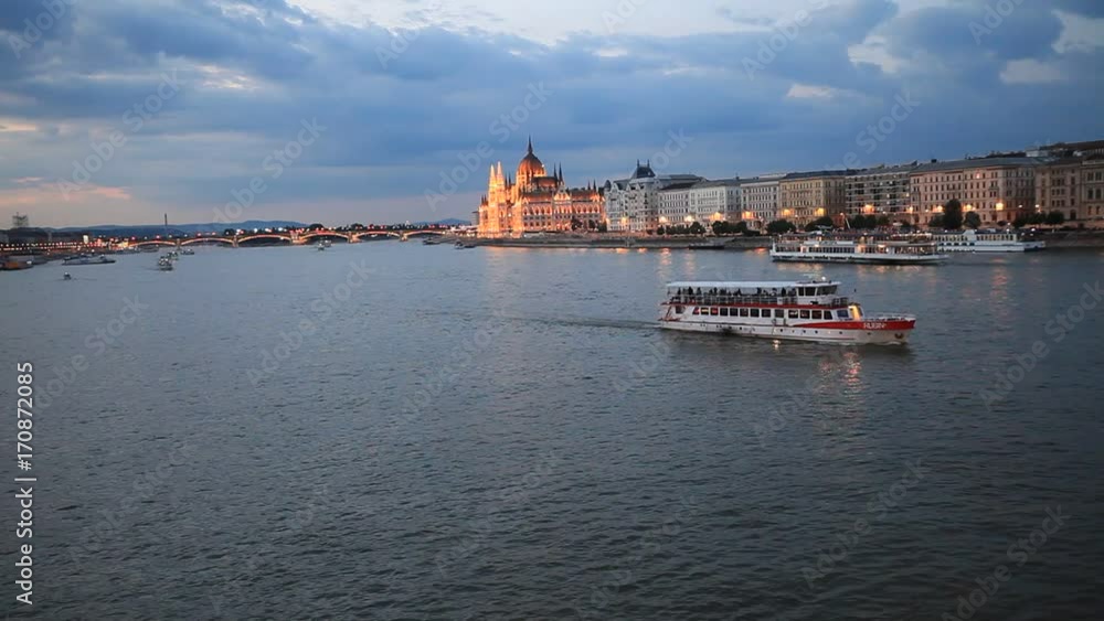 The picturesque landscape of the Parliament in Budapest, Hungary after the sunset. Cruise ships crossing the Danube river. The picturesque landscape of the Parliament in Budapest, Hungary after the sunset. Cruise ships crossing the Danube river.