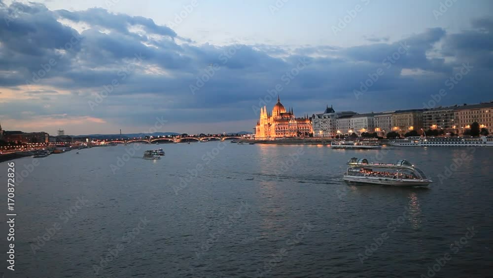 The picturesque landscape of the Parliament in Budapest, Hungary after the sunset. Cruise ships crossing the Danube river. The picturesque landscape of the Parliament in Budapest, Hungary after the sunset. Cruise ships crossing the Danube river.