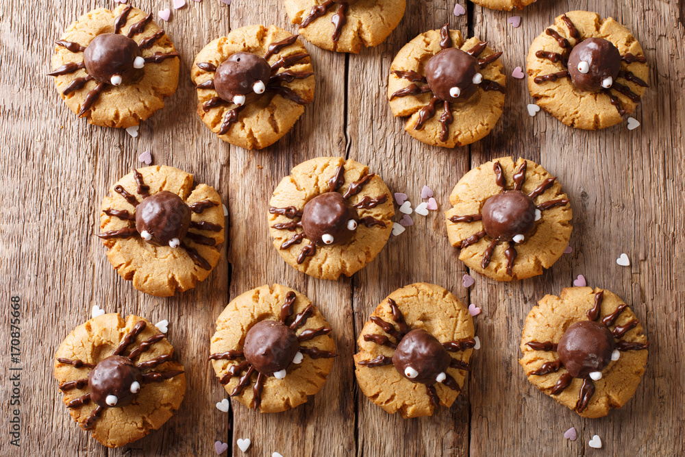 Halloween cookies with chocolate spiders close-up on a wooden table. horizontal top view