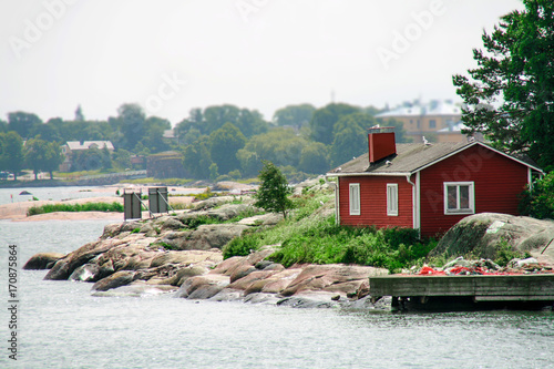 A small idyllic red cabin on a small islet the coast near Helsinki, Finland