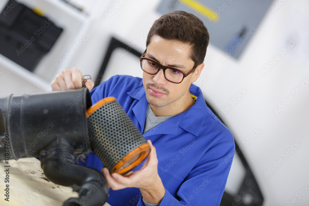 professional mechanic cleaning filter in his workshop - obrazy, fototapety, plakaty 