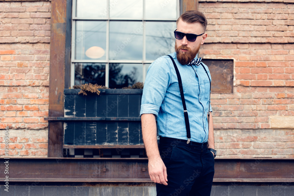 young guy with a beard and mustache with glasses posing on the street in the sunlight, fashion man, style, vintage style, retro men, handsome beard, outdoor portrait, hipster man