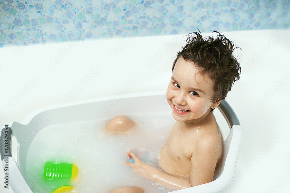 a happy child bathes in a bathroom. Little baby having soapy bath at home a happy child bathes in a bathroom. Little baby having soapy bath at home