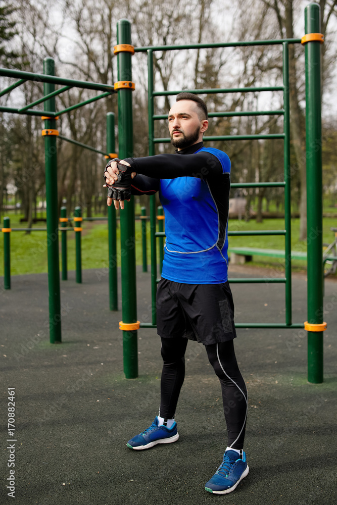 Obraz premium Young strong man stretches his muscles before training
