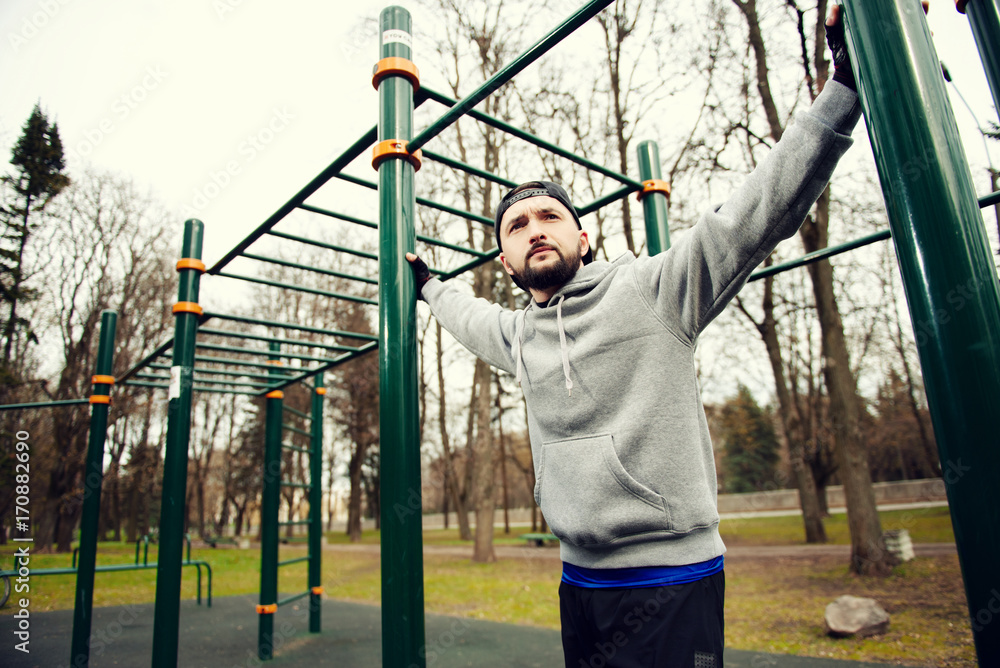 Young strong man prepares for training on a sports field in the summer in the city Young strong man prepares for training on a sports field in the summer in the city