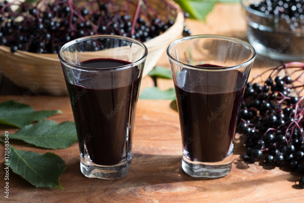 Two glasses of elderberry syrup on a wooden background Two glasses of elderberry syrup on a wooden background