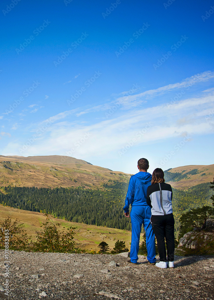 Couple standing on the cliff looking at Carpathian mountains