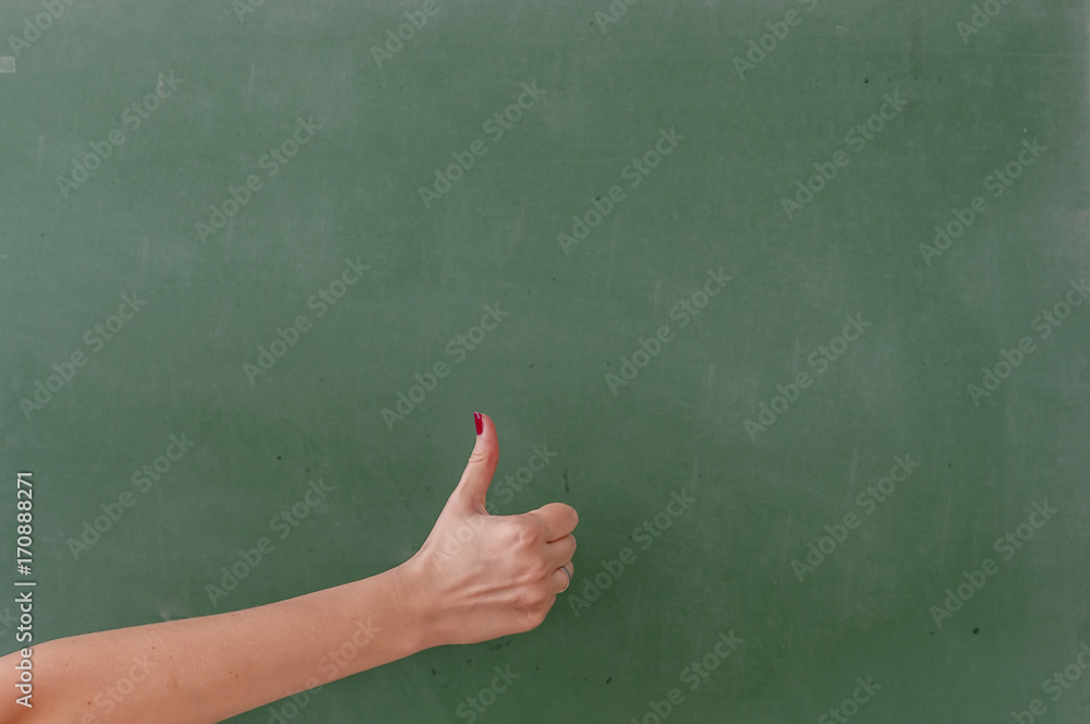 Like this. Close-up of human hand with thumb up in front of the blackboard Like this. Close-up of human hand with thumb up in front of the blackboard
