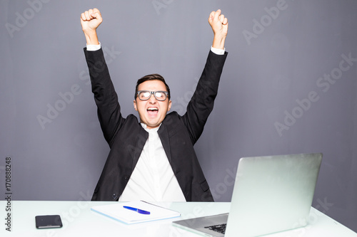 Happy businessman completed task and triumphing with raised hands