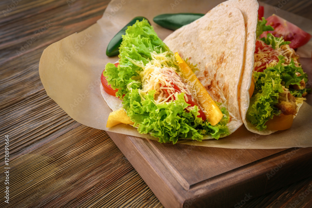 Wooden board with delicious fish tacos on kitchen table Wooden board with delicious fish tacos on kitchen table