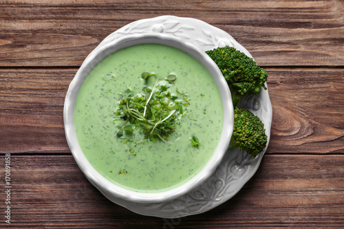 Bowl with tasty broccoli soup on wooden background
