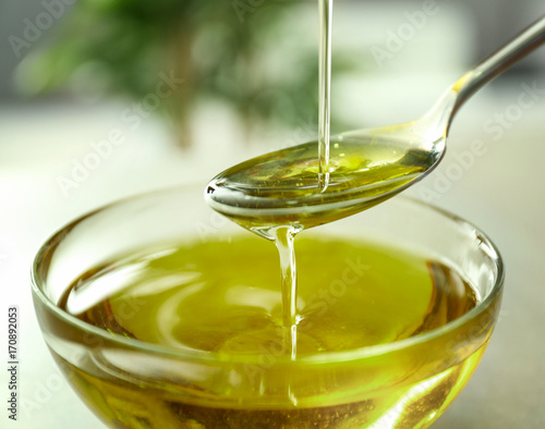 Pouring hemp oil into glass bowl on blurred background