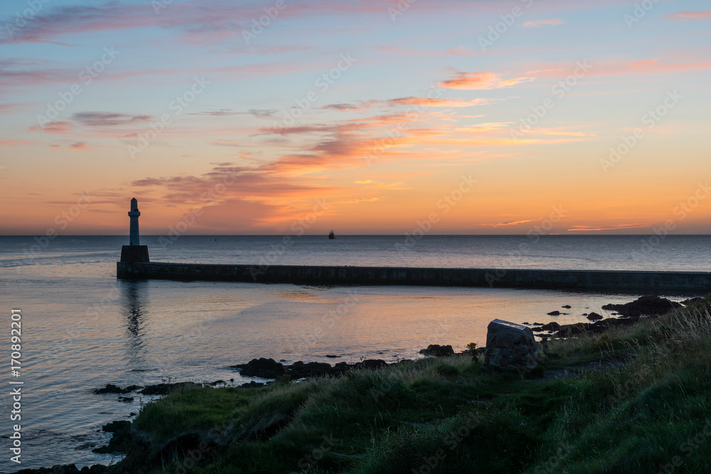 Sea wall, lighthouse and sunrise.